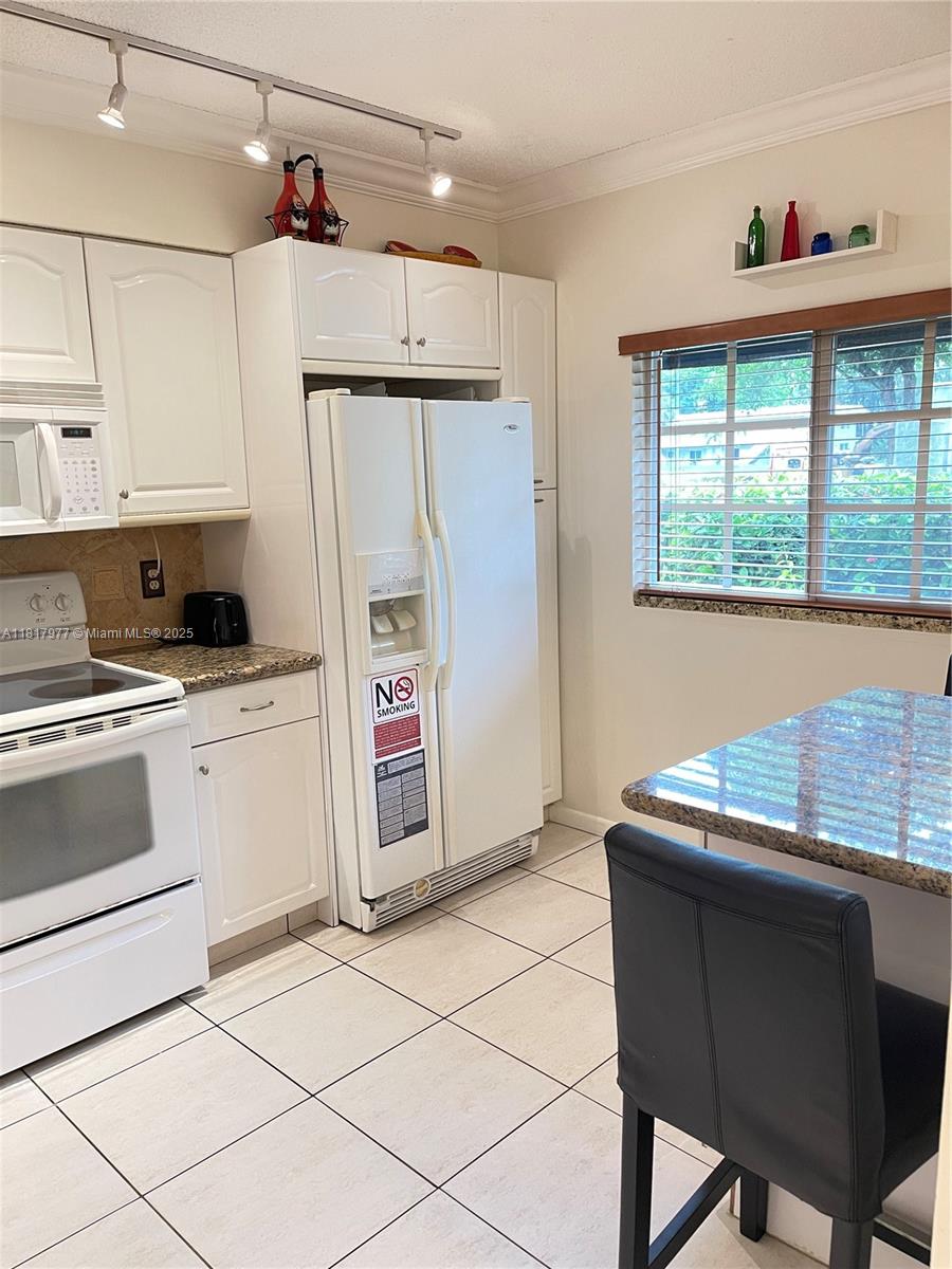 4000 Crystal Lake Drive, Unit 111 Deerfield Beach, FL 33064 - Photo 5 of 26 a kitchen with stainless steel appliances kitchen island granite countertop a refrigerator and a stove top oven