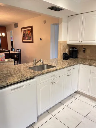 a kitchen with granite countertop white cabinets and sink
