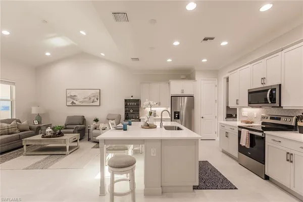 a kitchen with stainless steel appliances kitchen island granite countertop a sink and a refrigerator