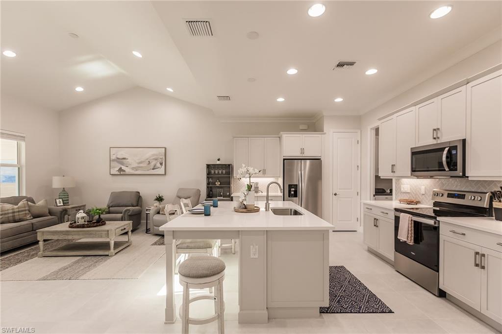 7263 Cayo Coco Lane Naples, FL 34113 - Photo 15 of 44 a kitchen with stainless steel appliances kitchen island granite countertop a sink and a refrigerator