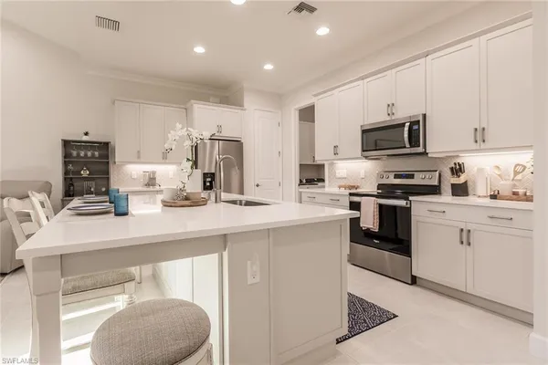 a kitchen with kitchen island a sink a stove a microwave a refrigerator a counter top space and cabinets