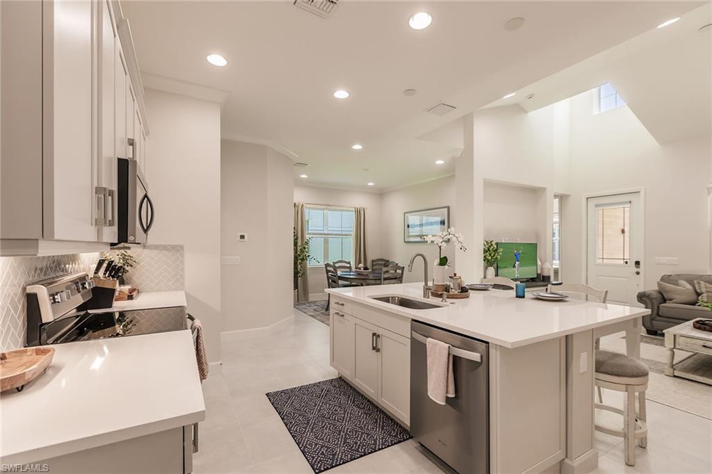 7263 Cayo Coco Lane Naples, FL 34113 - Photo 17 of 44 a kitchen that has a sink a stove and chairs