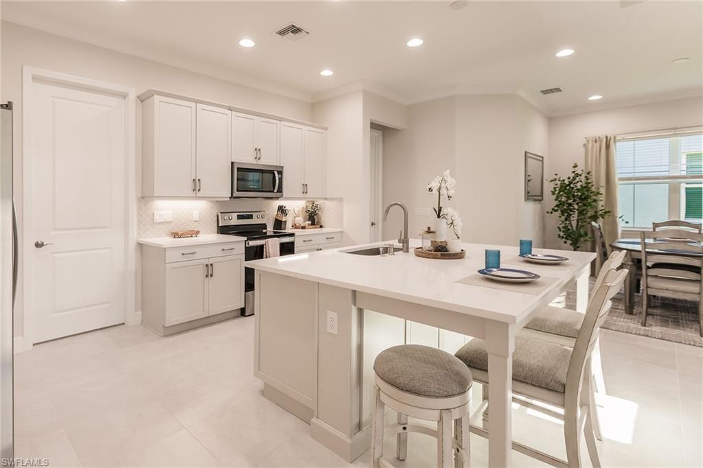 7263 Cayo Coco Lane Naples, FL 34113 - Photo 18 of 44 a kitchen with stainless steel appliances granite countertop a white cabinets and chairs