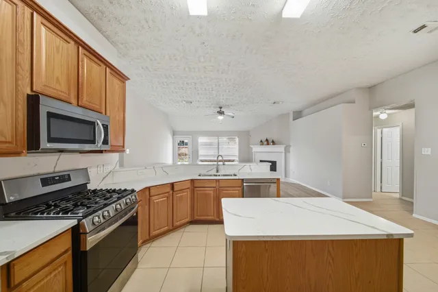a large kitchen with granite countertop a sink refrigerator and cabinets
