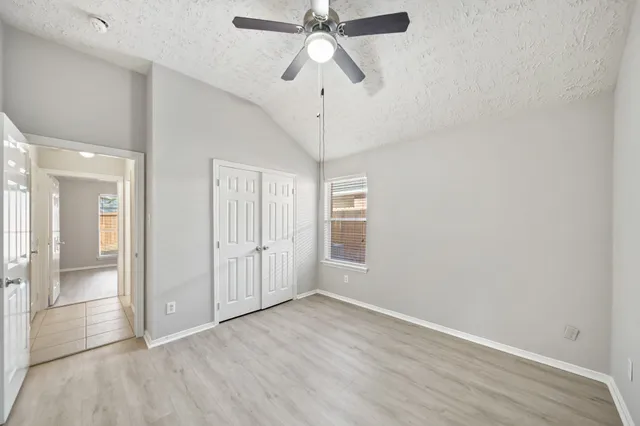 an empty room with wooden floor ceiling fan and windows
