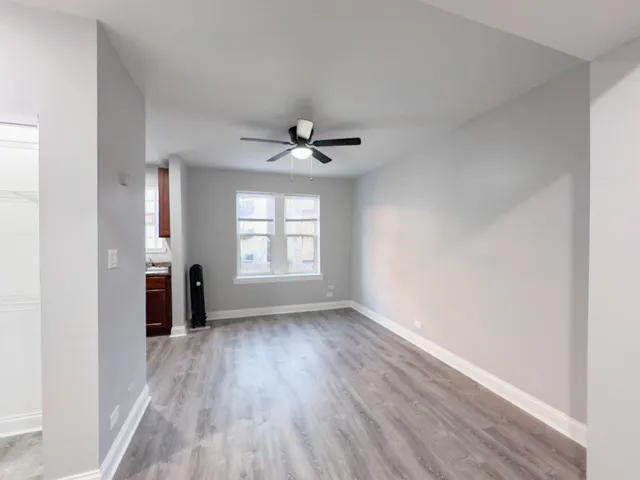 an empty room with wooden floor fan and windows