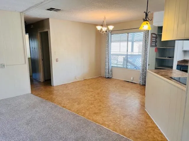 an empty room with a fireplace and chandelier