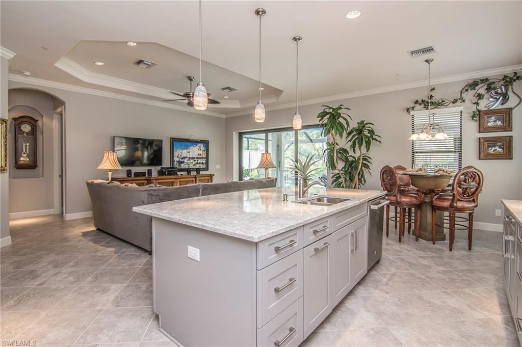 10249 Coconut Road Estero, FL 34135 - Photo 10 of 27 a kitchen with kitchen island a counter top space appliances and a dining table
