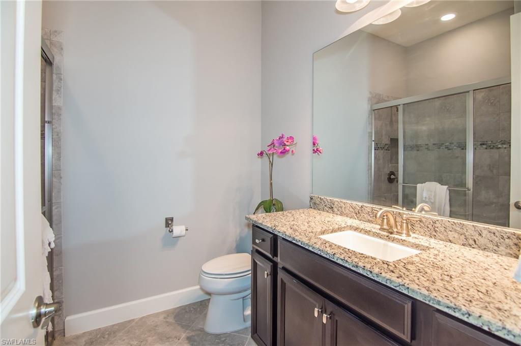 10249 Coconut Road Estero, FL 34135 - Photo 20 of 27 a bathroom with a granite countertop sink a mirror and a toilet