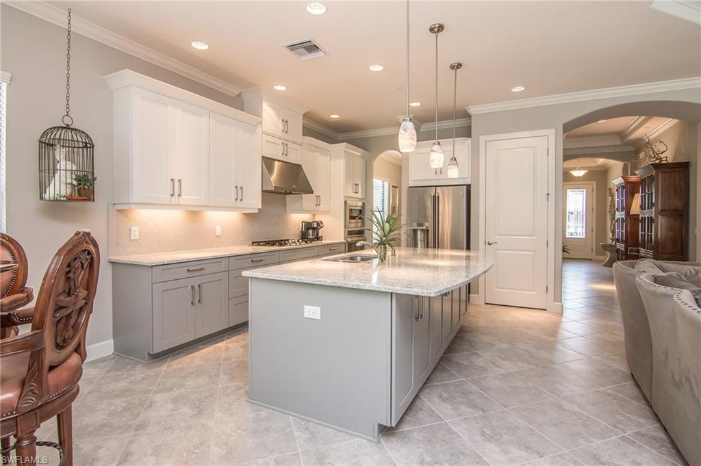 10249 Coconut Road Estero, FL 34135 - Photo 27 of 27 a large kitchen with kitchen island a sink a stove a dining table and chairs