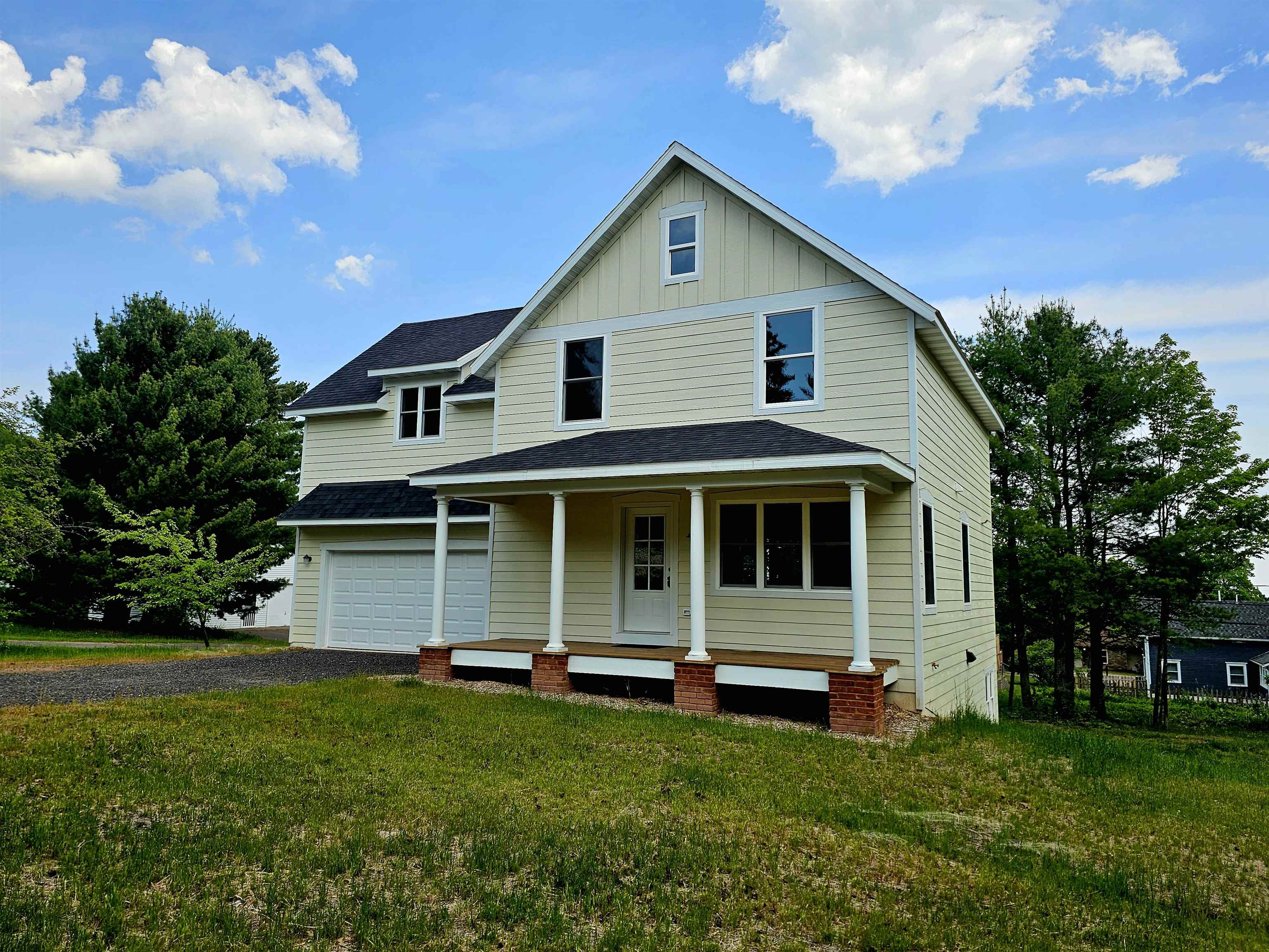 2 8th Street Bayfield, WI 54814 - Photo 1 of 24 View of front of property with driveway, covered porch, board and batten siding, an attached garage, and roof with shingles