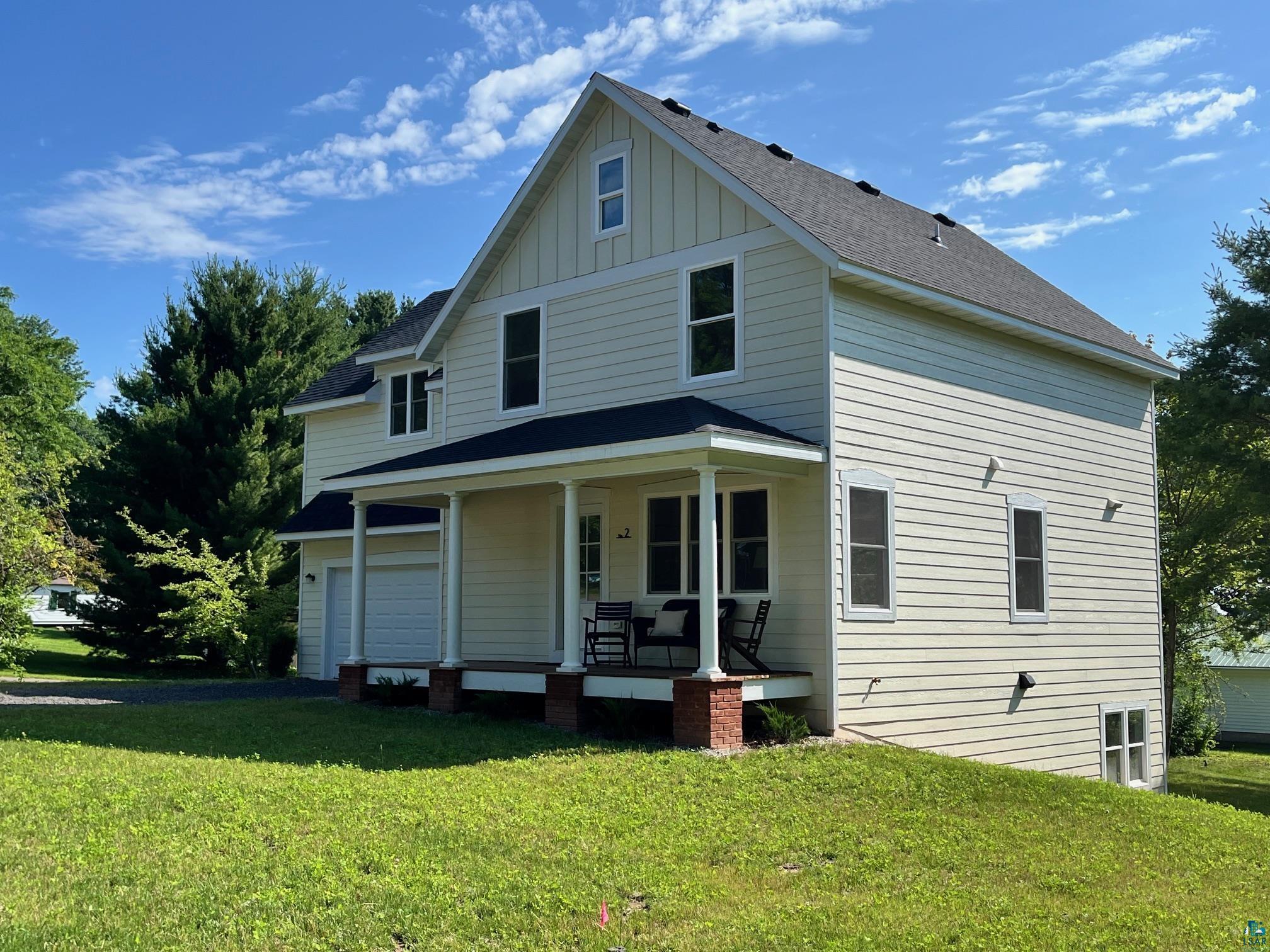 2 8th Street Bayfield, WI 54814 - Photo 22 of 24 View of front of property featuring covered porch, board and batten siding, a front yard, a shingled roof, and asphalt driveway