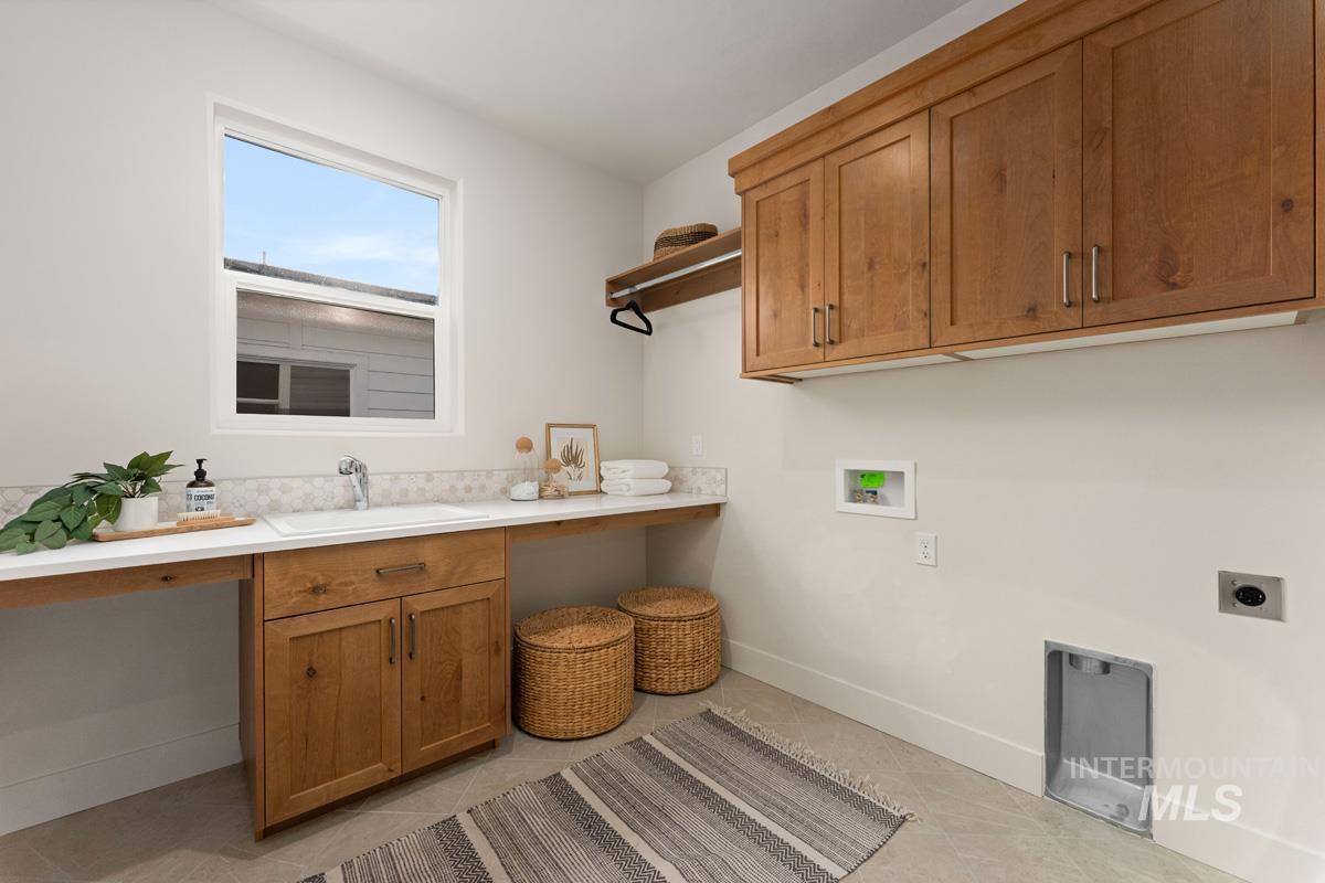 13338 North Spring Creek Way Boise, ID 83714 - Photo 32 of 46 Laundry room featuring a single basin sink, light wood-finish cabinetry, quartz countertops, white tile backsplash, and upper wall-mounted storage