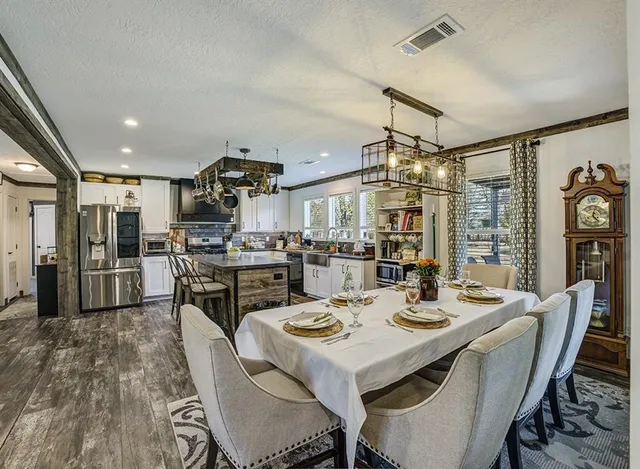 a kitchen with a dining table chairs stainless steel appliances and cabinets