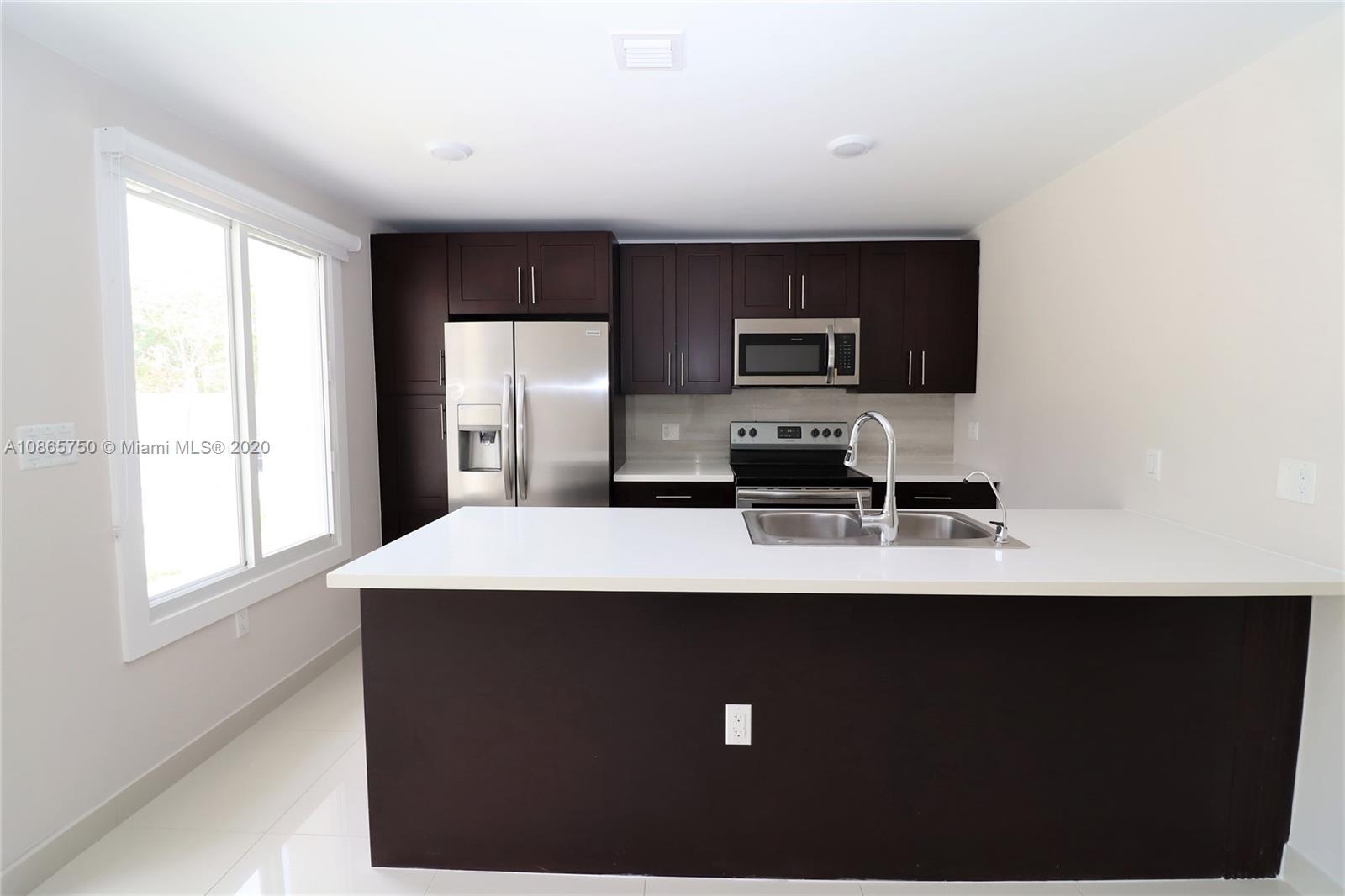 13966 Southwest 259th Terrace Homestead, FL 33032 - Photo 9 of 27 a kitchen with kitchen island a sink a stove a microwave a refrigerator with grey cabinets and wooden floor