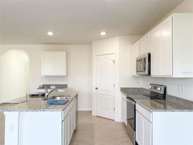 a kitchen with granite countertop a sink a stove and a refrigerator
