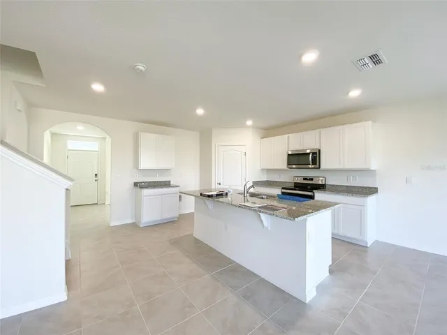 a kitchen with stainless steel appliances a sink a stove a microwave a counter top space and cabinets