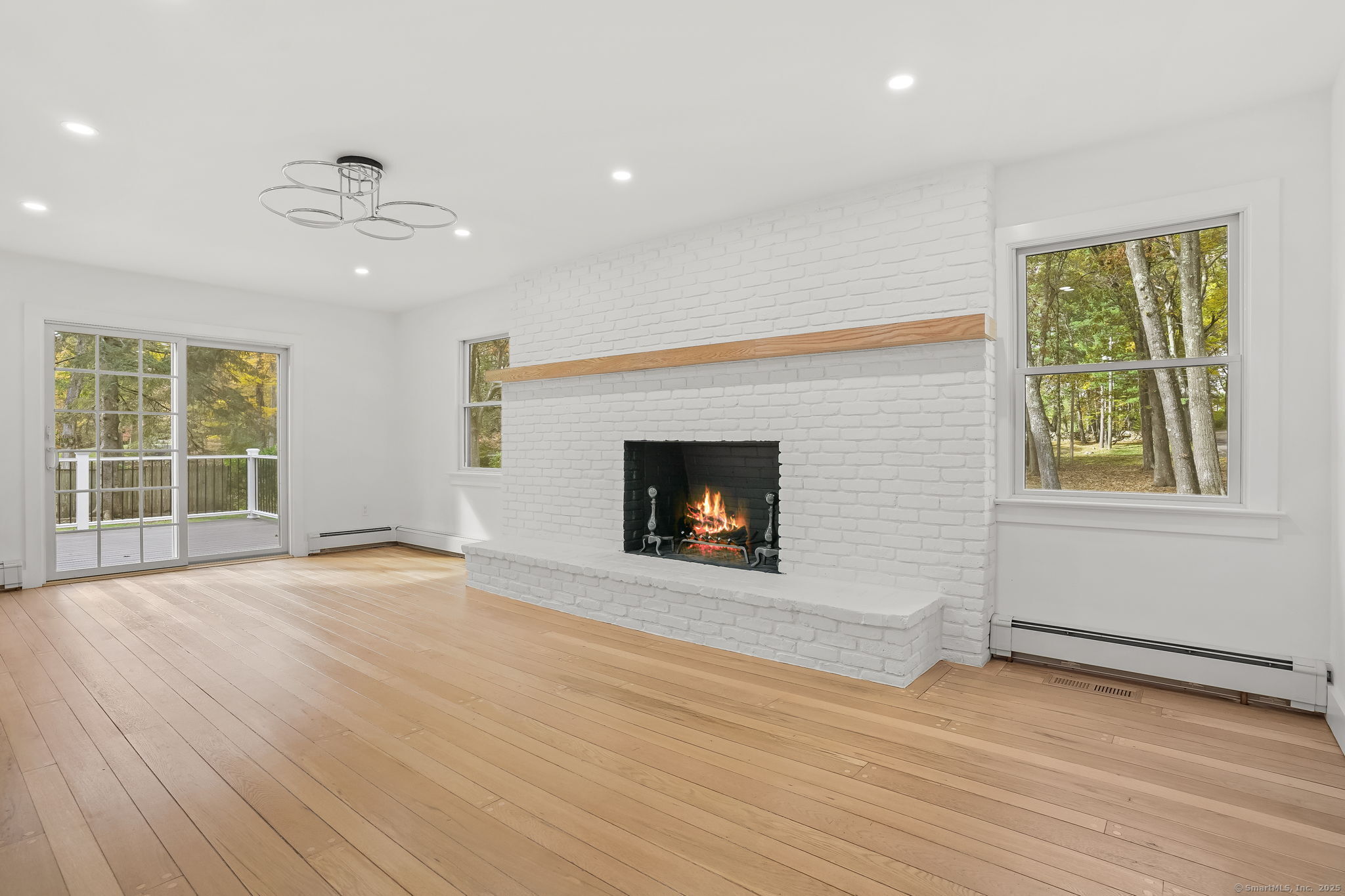 4 Trails End Road Weston, CT 06883 - Photo 29 of 40 an empty room with windows fireplace and wooden floor