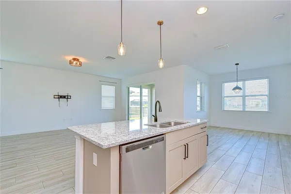 a kitchen with granite countertop kitchen island stainless steel appliances a sink cabinets and wooden floor