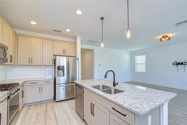 a kitchen with stainless steel appliances granite countertop a refrigerator a stove and a sink with wooden floor