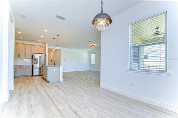 an empty room with wooden floor a chandelier fan and windows