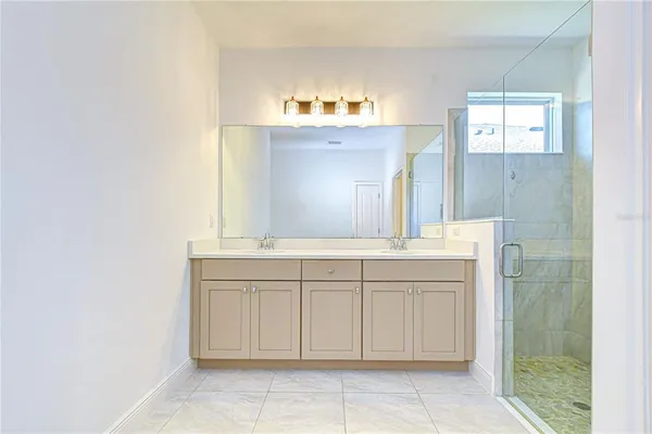 a bathroom with a double vanity sink mirror and shower