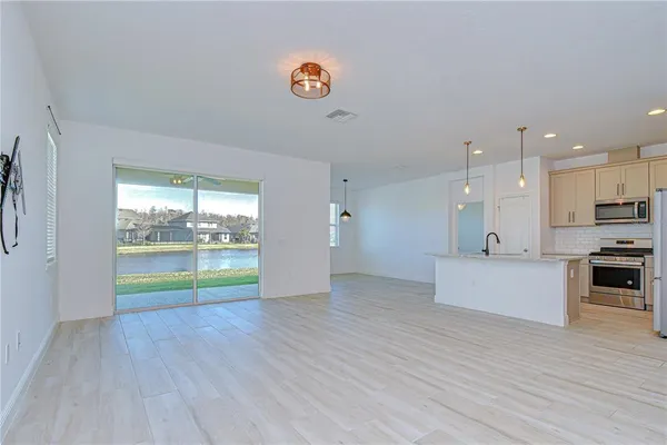 a view of an empty room with window and wooden floor