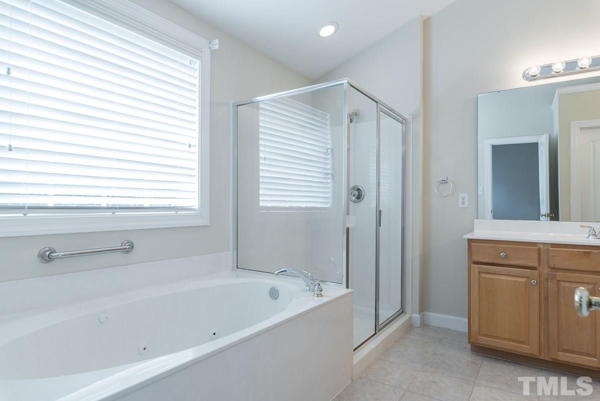 12227 Orchardgrass Lane Raleigh, NC 27614 - Photo 17 of 25 a bathroom with a bathtub a mirror a vanity and a shower