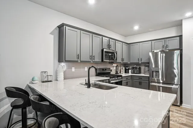 a kitchen with granite countertop a refrigerator a stove a sink a stove a dining table and chairs