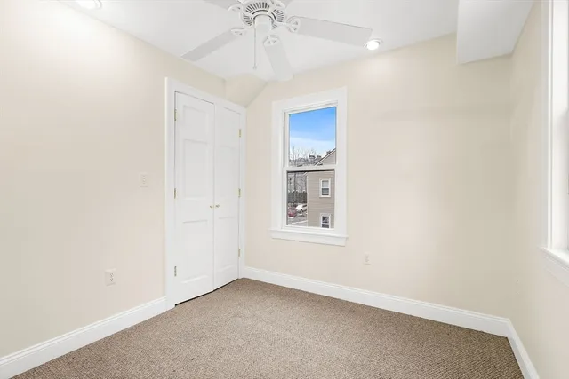 an empty room with windows and fan