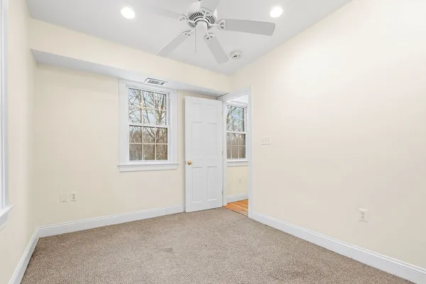 an empty room with windows and fan