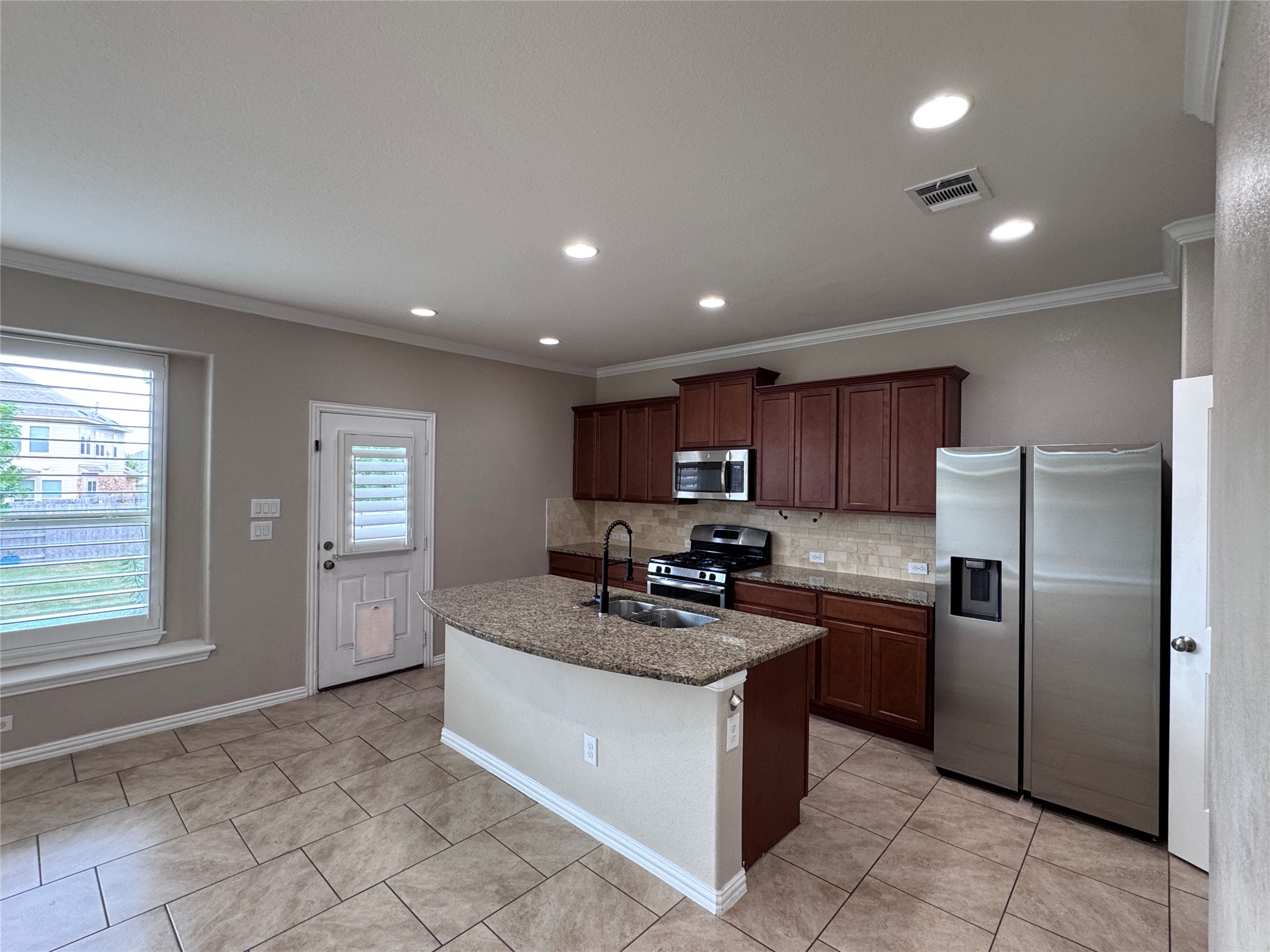 2605 Rough Berry Road Pflugerville, TX 78660 - Photo 11 of 40 A well-appointed kitchen features a central island, rich cabinetry, and sleek stainless steel appliances.
