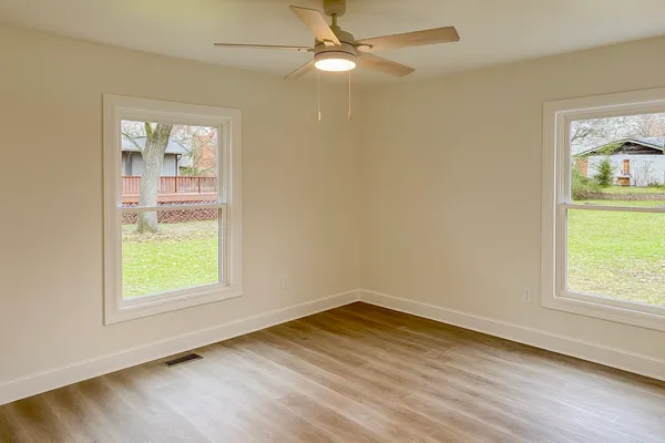 a view of an empty room with wooden floor and a window