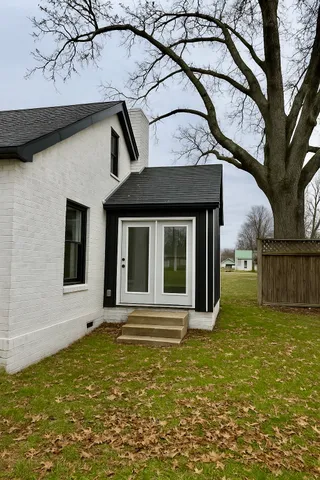 a view of a house with a small yard and a large tree