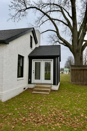 a view of a house with a small yard and a large tree