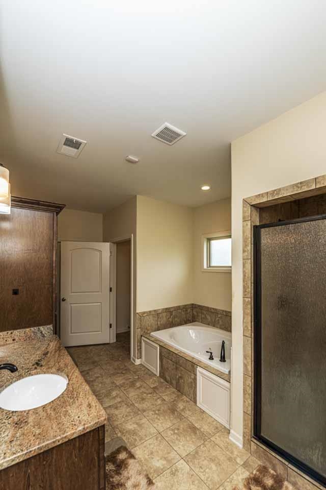 185 Belmont Road Mason, TN 38049 - Photo 15 of 38 Bathroom featuring a jetted soaking tub with tiled surround, a separate shower enclosure with textured glass, tile flooring, a single vanity with stone-finish countertop, and dark wood-finish cabinetry