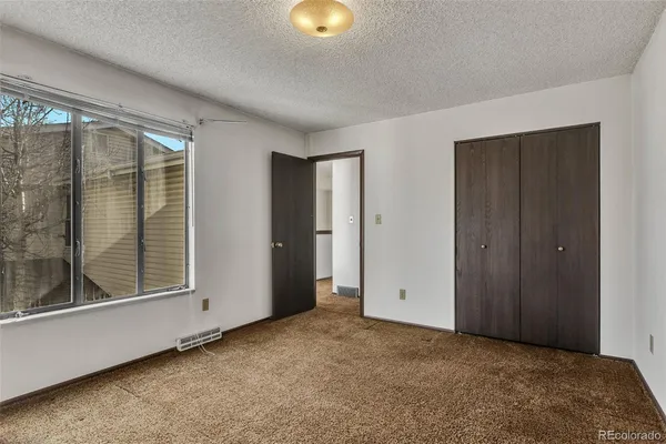 a view of an empty room with window and closet area
