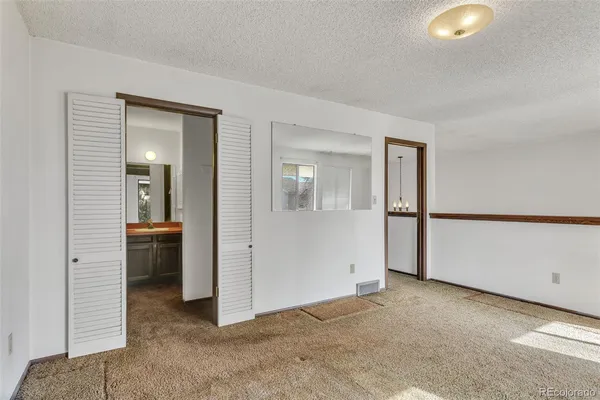 an empty room with closet and mirrors