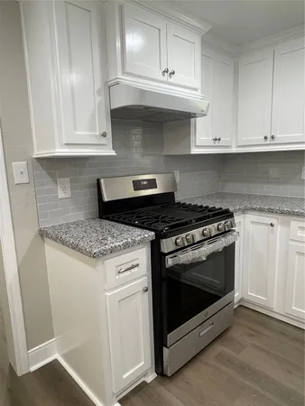 a kitchen with granite countertop white cabinets and stainless steel appliances
