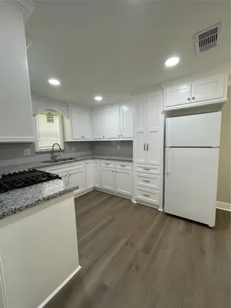a kitchen with granite countertop white cabinets and white appliances