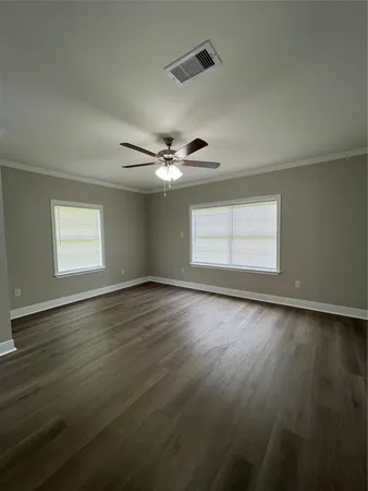 a view of an empty room with wooden floor and a window