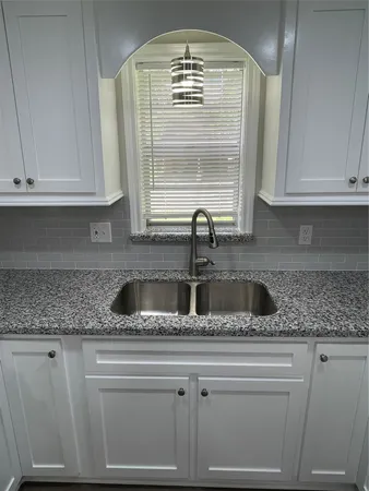 a kitchen with granite countertop a sink window and cabinets