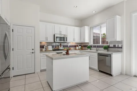 a kitchen with granite countertop white cabinets and stainless steel appliances