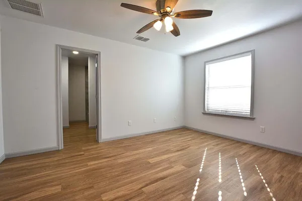 a view of an empty room with wooden floor and a window