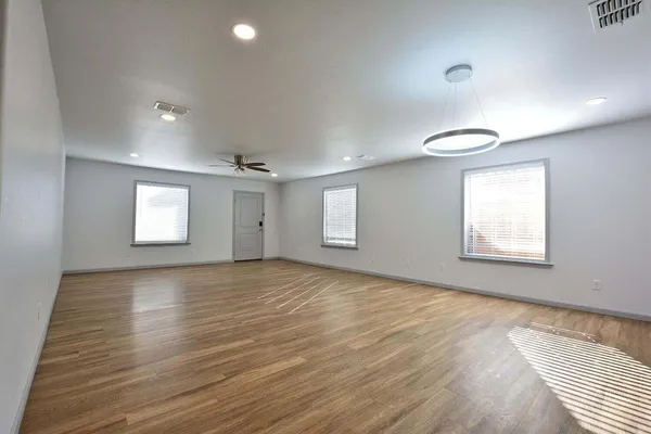 an empty room with wooden floor and windows