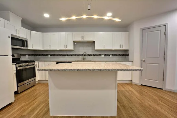 a kitchen with stainless steel appliances granite countertop a stove a sink and a microwave
