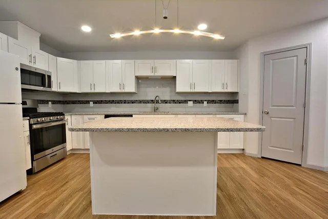 a kitchen with stainless steel appliances granite countertop a stove a sink and a microwave