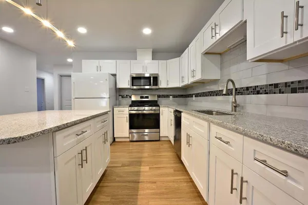a large kitchen with stainless steel appliances granite countertop a sink and cabinets