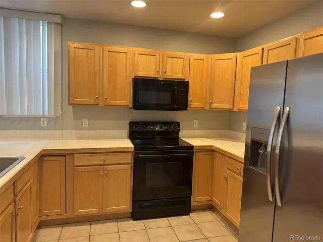 a kitchen with granite countertop a stove top oven microwave and refrigerator