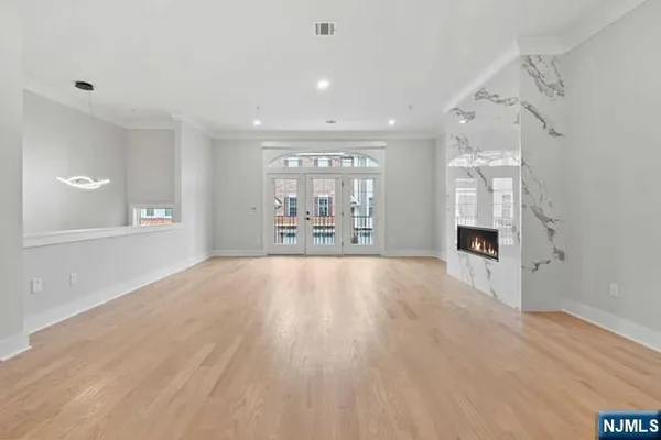 a view of an empty room with wooden floor and window